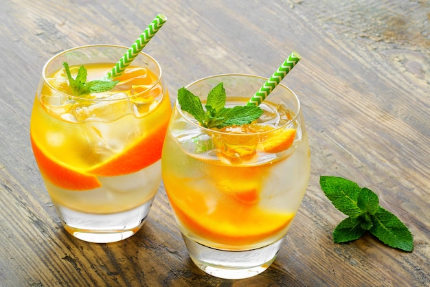 Preparación de la bebida de limonada. Limonada en dos vasos y limón con menta en la mesa al aire libre.