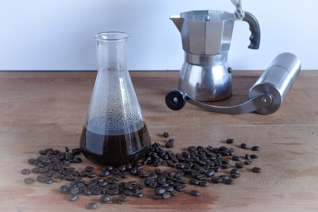 Preparación de café caliente en tubo de laboratorio con granos de café en la mesa de madera.