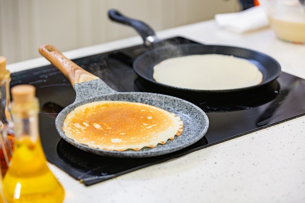 Preparación de la cocina: el chef fríe panqueques frescos en dos sartenes