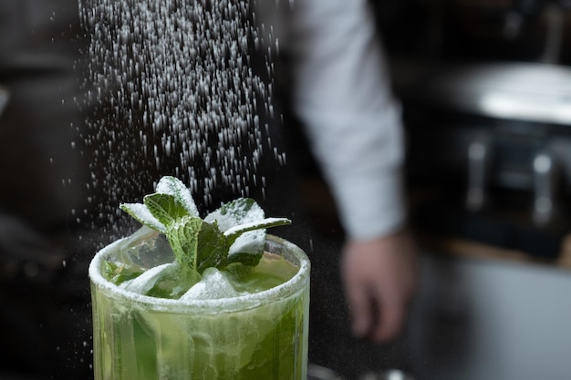 Preparación de un cóctel mojito por un camarero en un bar Bebida alcohólica fresca de verano