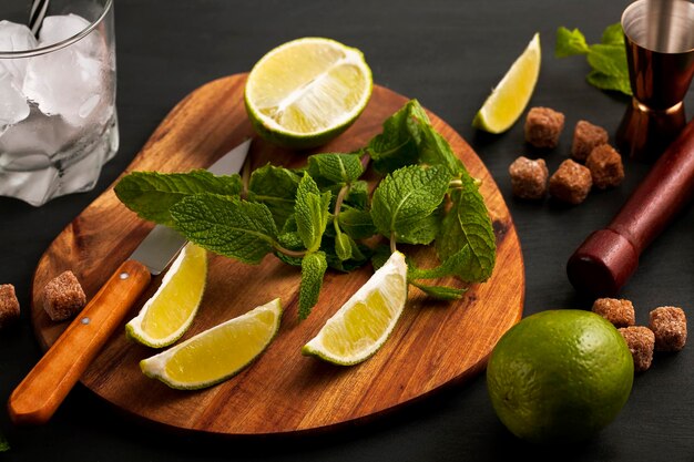 Foto preparación del cóctel mojito utensilios y ingredientes del bar menta limón hielo y azúcar de caña vista superior con espacio de copia