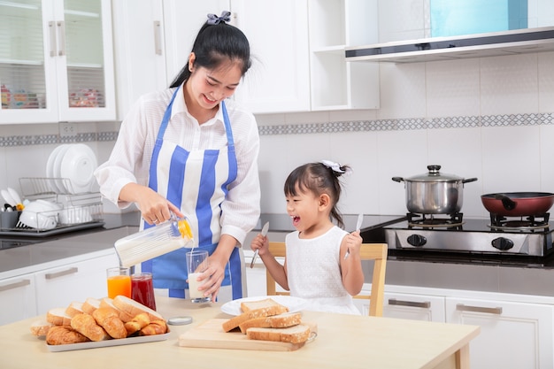 Preparación de un desayuno familiar. La madre asiática y la hija del bebé cocinan el desayuno por mañana.