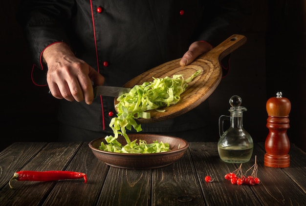 Preparación de ensalada de repollo Chef profesional mientras trabaja en la cocina del restaurante