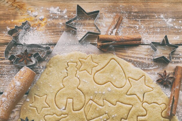 Preparación de galletas caseras de Navidad o Año Nuevo con moldes sobre papel pergamino artesanal sobre tablas de madera