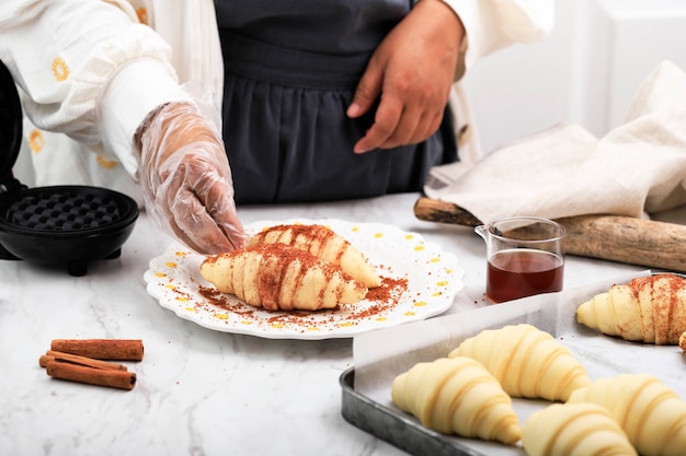 Preparación para hacer Croffle: Chef femenina recubriendo masa cruda de croissant con azúcar de palma y canela en polvo