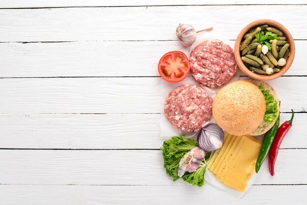 Preparación de hamburguesa Carne tomates cebollas Sobre un fondo blanco de madera Vista superior Espacio de copia libre