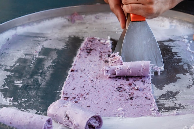 preparación de helados, comida callejera tailandesa. cocinar expertamente tuerce el morado congelado en rollos