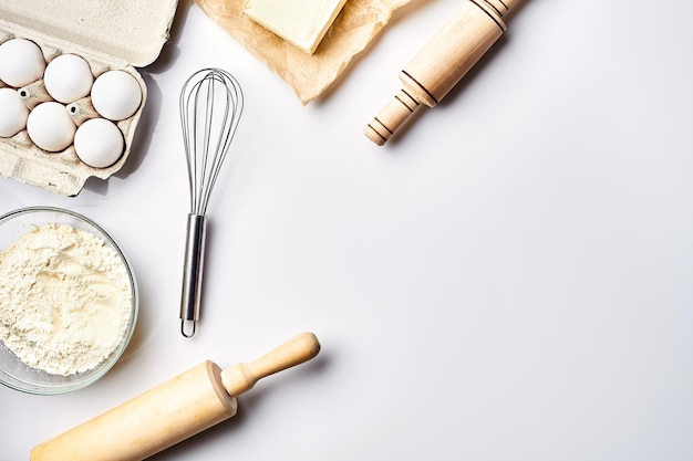 Foto preparación de la masa ingredientes para la masa harina mantequilla huevos y varias herramientas sobre fondo blanco espacio libre para texto vista superior