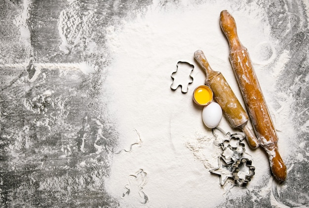 Preparación de la masa Ingredientes para la masa: huevos con harina y rodillos sobre la mesa de piedra