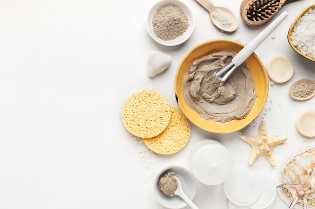 Preparación de mascarilla facial cosmética natural en cuenco de cerámica sobre fondo blanco.