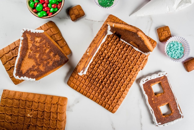 Preparación para Navidad, año nuevo. Cocina y decoración de la casa de pan de jengibre de adviento tradicional, vista superior, mármol blanco.