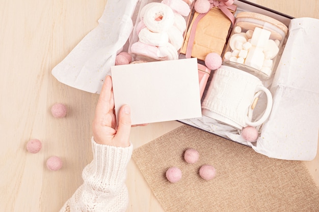 Preparación del paquete de cuidado y caja de regalo de temporada con caja de malvavisco, té, café o cacao y adorno navideño