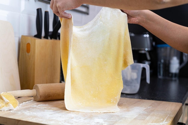 Preparación de pasta casera Una persona estirando un gran trozo de pasta