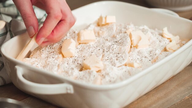 Preparación de patatas gratinadas en una fuente para horno de cerámica blanca.