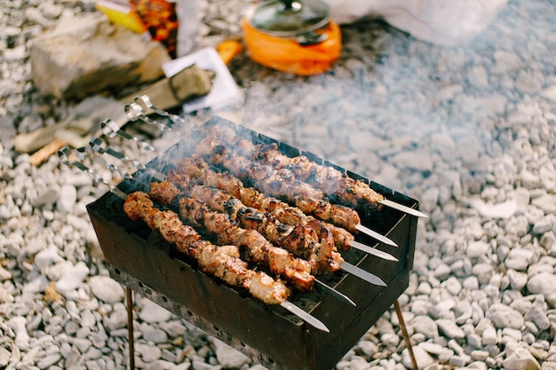 Preparación de pinchito marinado en una parrilla sobre carbón con humo