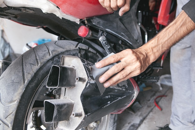 Preparación para pintar una motocicleta. Mano en un papel de lija