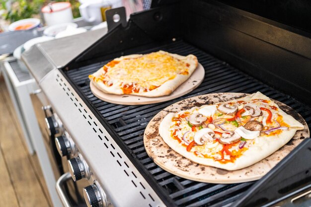 Preparación de pizzas a la parrilla individuales en una parrilla de gas al aire libre.