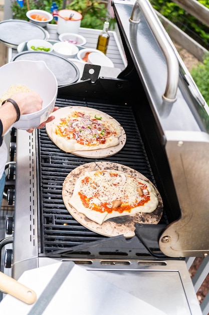 Preparación de pizzas a la parrilla individuales en una parrilla de gas al aire libre.