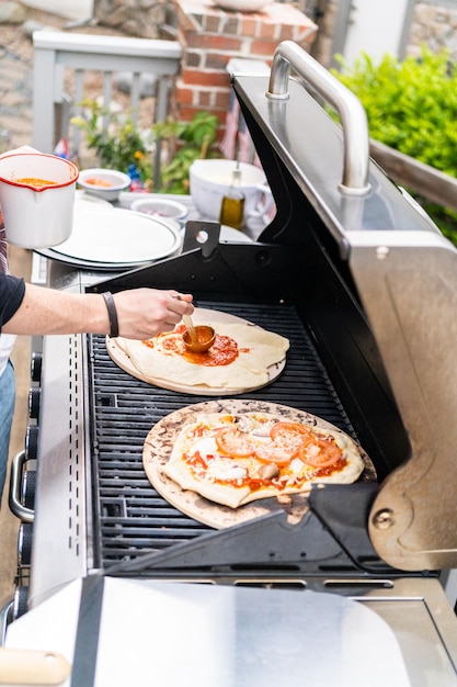 Preparación de pizzas a la parrilla individuales en una parrilla de gas al aire libre.