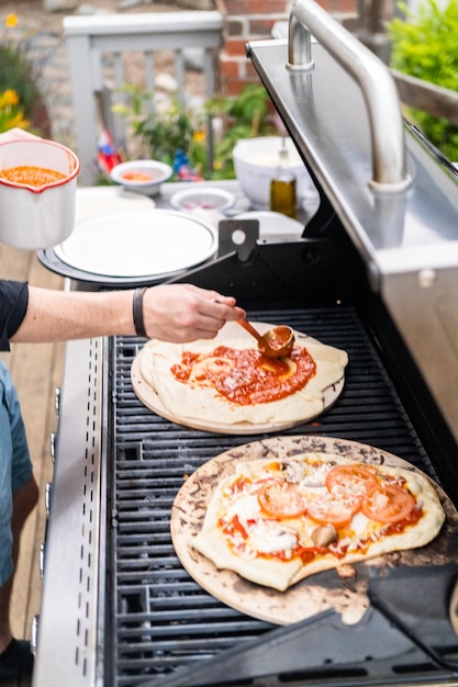 Preparación de pizzas a la parrilla individuales en una parrilla de gas al aire libre.
