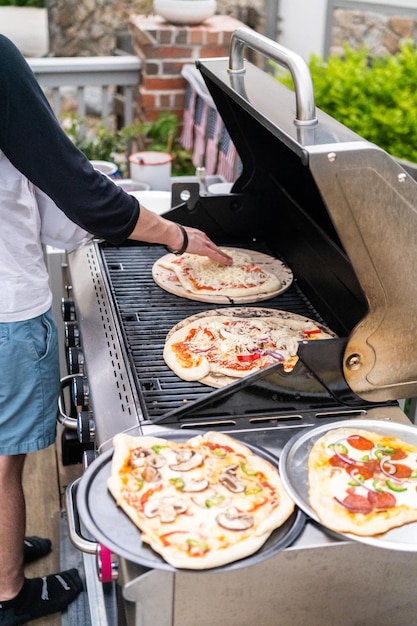 Preparación de pizzas a la parrilla individuales en una parrilla de gas al aire libre.