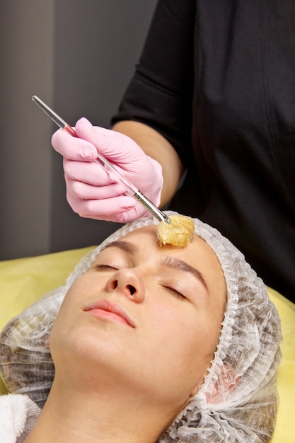 Preparación para procedimientos en la oficina de cosmetóloga. aplicando el gel a la cara con un cepillo especial.