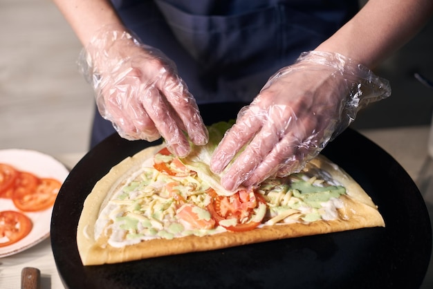 Preparación del proceso de pizza italiana Chef manos en guantes de una sola vez manteniendo rodajas de salmón sobre masa de pizza Vista de enfoque frontal