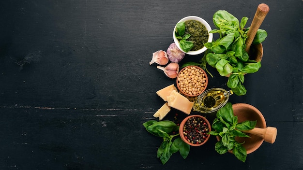 Preparación de salsa de pesto de albahaca Albahaca queso parmesano aceite de oliva Vista superior Sobre un fondo de madera negra Espacio libre para texto