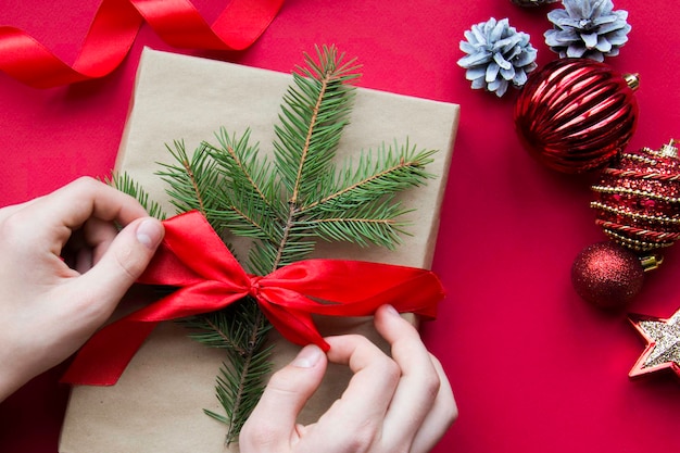 Preparación para las vacaciones. Año Nuevo y Navidad. decoración de regalo. Regalo de Navidad en las manos. Fondo rojo. fiesta. Año nuevo