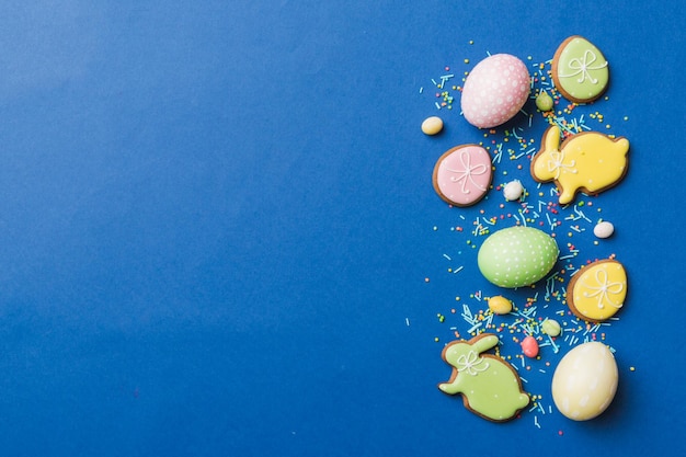 Preparación de vacaciones Huevos de Pascua de varios colores con galletas sobre fondo de color Concepto de vacaciones de huevos de Pascua de color pastel con espacio de copia