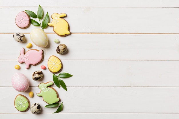 Preparación de vacaciones Huevos de Pascua de varios colores con galletas sobre fondo de color Concepto de vacaciones de huevos de Pascua de color pastel con espacio de copia