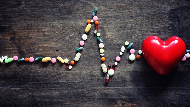 Preparaciones médicas para el tratamiento de enfermedades cardíacas. El concepto de dependencia de la salud del corazón en tabletas. Pastillas y estetoscopio sobre fondo de madera.