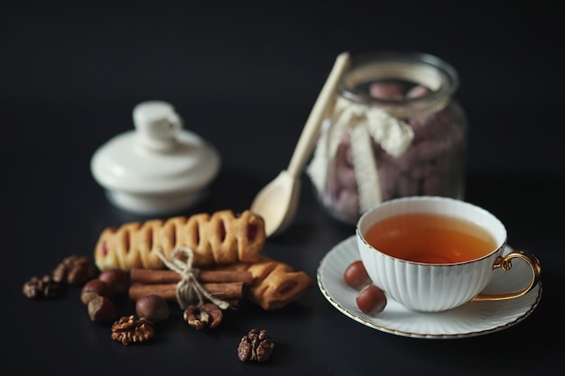 Preparado para el desayuno. Dulces y pasteles con nueces para té sobre fondo negro. Una taza de café y empanadas.