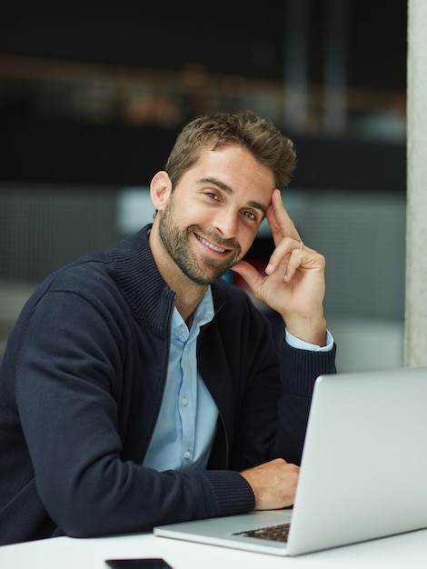 Preparado para ser alucinante con una estrategia impresionante. Retrato recortado de un apuesto joven hombre de negocios sentado solo en un espacio de oficina y usando su computadora portátil.