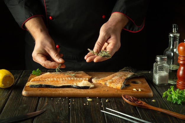 Preparamos peixe fresco numa tábua de cortar da cozinha antes de o salgarmos com especiarias aromáticas. Os cozinheiros adicionam alecrim ao bife de peixe.