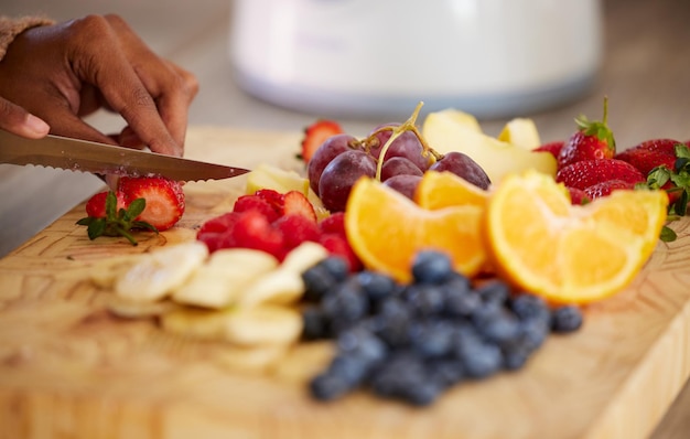 Foto preparando alguma bondade saudável para lanchar em closeup tiro de uma mulher irreconhecível cortando frutas frescas em casa