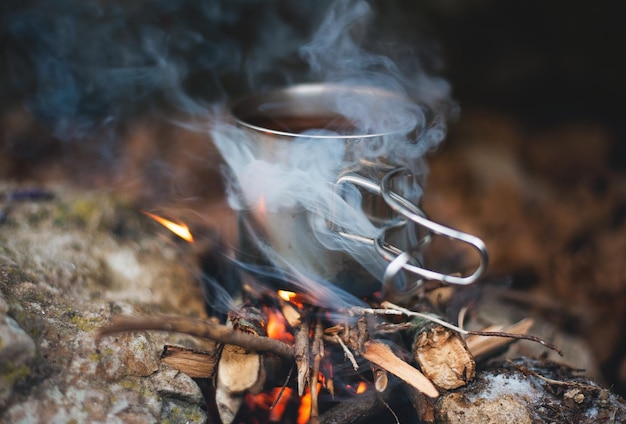 Foto preparando una bebida en una taza de metal en llamas en una caminata