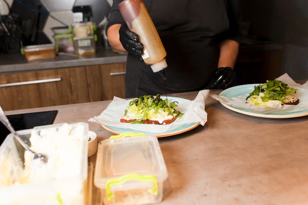 Preparando bruschettas vegetarianos saudáveis em luvas escuras.