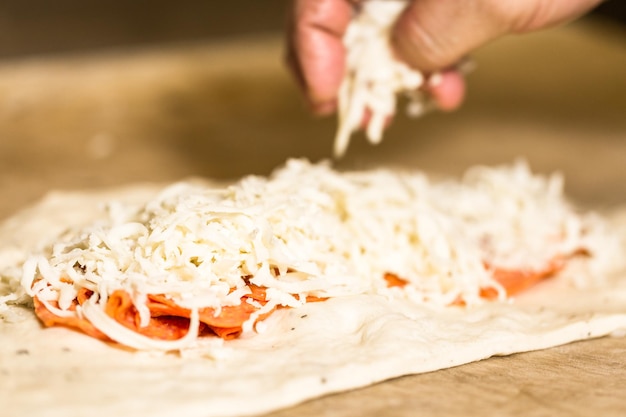 Preparando calzone de pepperoni con salsa de pizza y queso mozzarella.