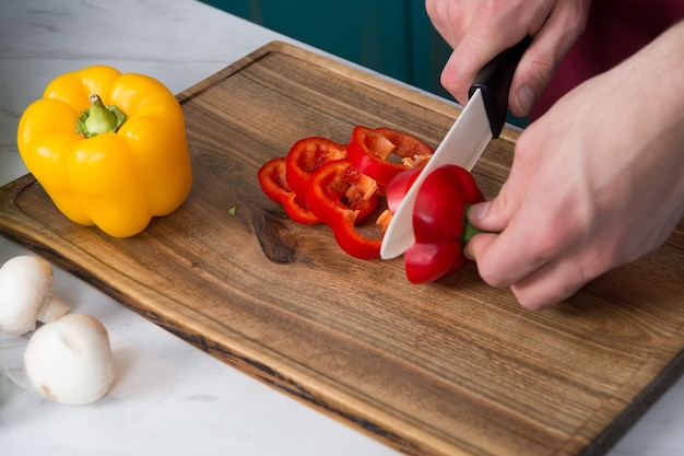 Preparando comida, chef cortando o pimentão vermelho.