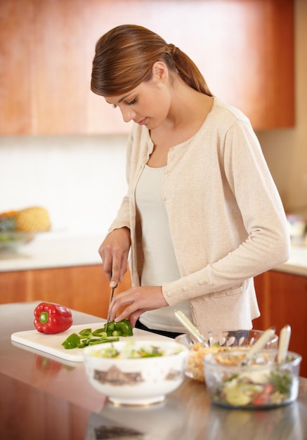 Preparando una comida Una mujer joven y atractiva cocinando en la cocina