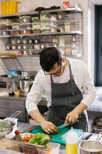 Preparando legumes para uma tigela deliciosa prato de um chef masculino em uma cozinha de restaurante contemporâneo