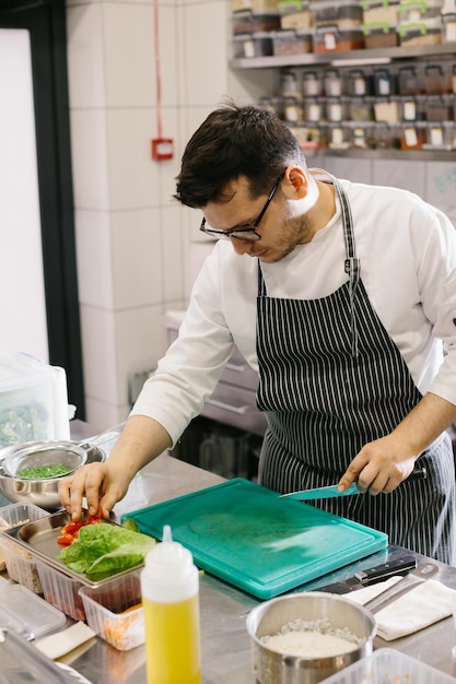 Preparando legumes para uma tigela deliciosa prato de um chef masculino em uma cozinha de restaurante contemporâneo