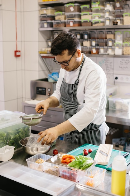 Preparando legumes para uma tigela deliciosa prato de um chef masculino em uma cozinha de restaurante contemporâneo