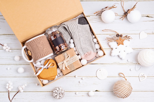 Preparando paquete de cuidados, caja regalo de temporada con té, galletas y calcetines de lana. Cesta ecológica personalizada para familiares y amigos para Navidad. Vista superior, endecha plana