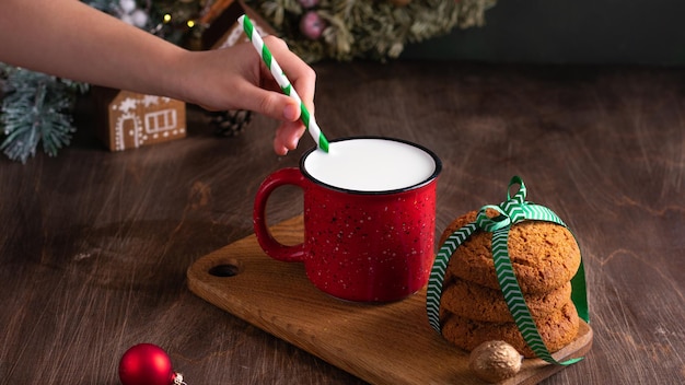 Preparando un regalo para Santa Claus Kid poniendo leche y galletas cerca del árbol de Navidad