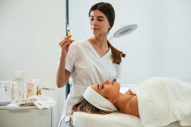 Foto preparando-se para a injeção rosto de mulher recebendo cuidados faciais por mãos de esteticista no salão de spa