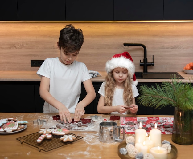 Preparando-se para as férias de Natal. Crianças - um menino e uma menina estão preparando pão de mel na cozinha