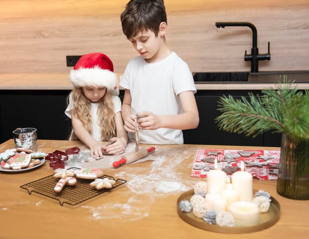 Preparando-se para as férias de Natal. Crianças - um menino e uma menina estão preparando pão de mel na cozinha
