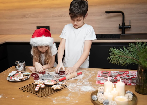 Preparando-se para as férias de Natal. Crianças - um menino e uma menina estão preparando pão de mel na cozinha